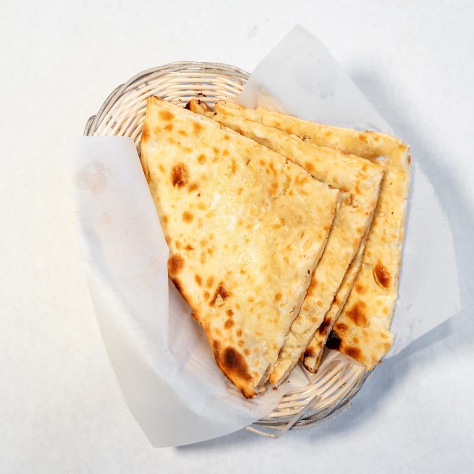 Basket of golden, toasted flatbread wedges lined with white paper.