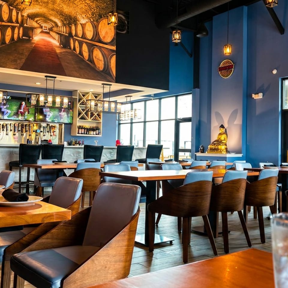 A modern restaurant interior with blue walls, wooden tables, a bar, and a large barrel mural.