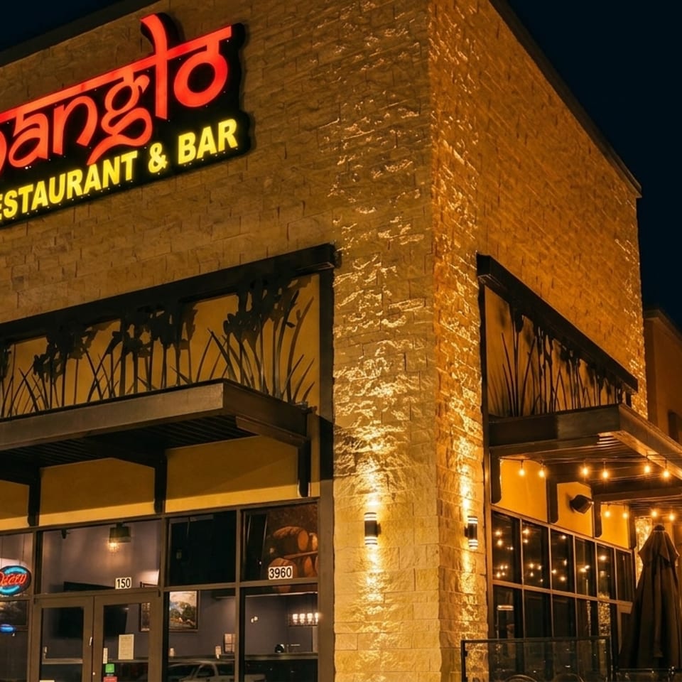 Nanglo Restaurant & Bar exterior at night, with glowing sign, string lights, and outdoor seating.